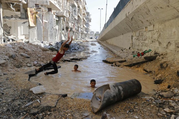 ©REUTERS Baz Ratner Сирия. Дети играют в яме с водой, образованной от взрыва в Алеппо.